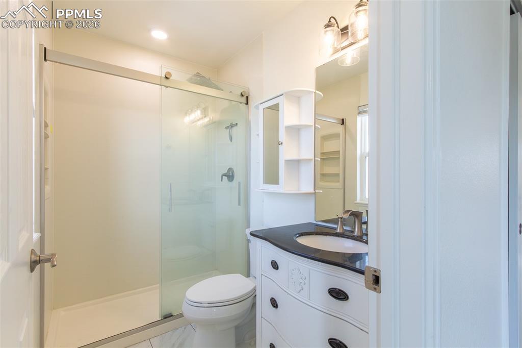 Image 33 of 38: Bathroom featuring a glass-enclosed shower, white toilet, and a vanity with