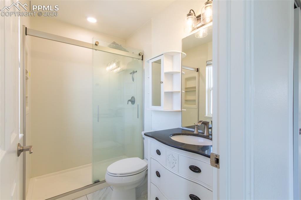 Image 33 of 41: Bathroom featuring a glass-enclosed shower, white toilet, and a vanity with