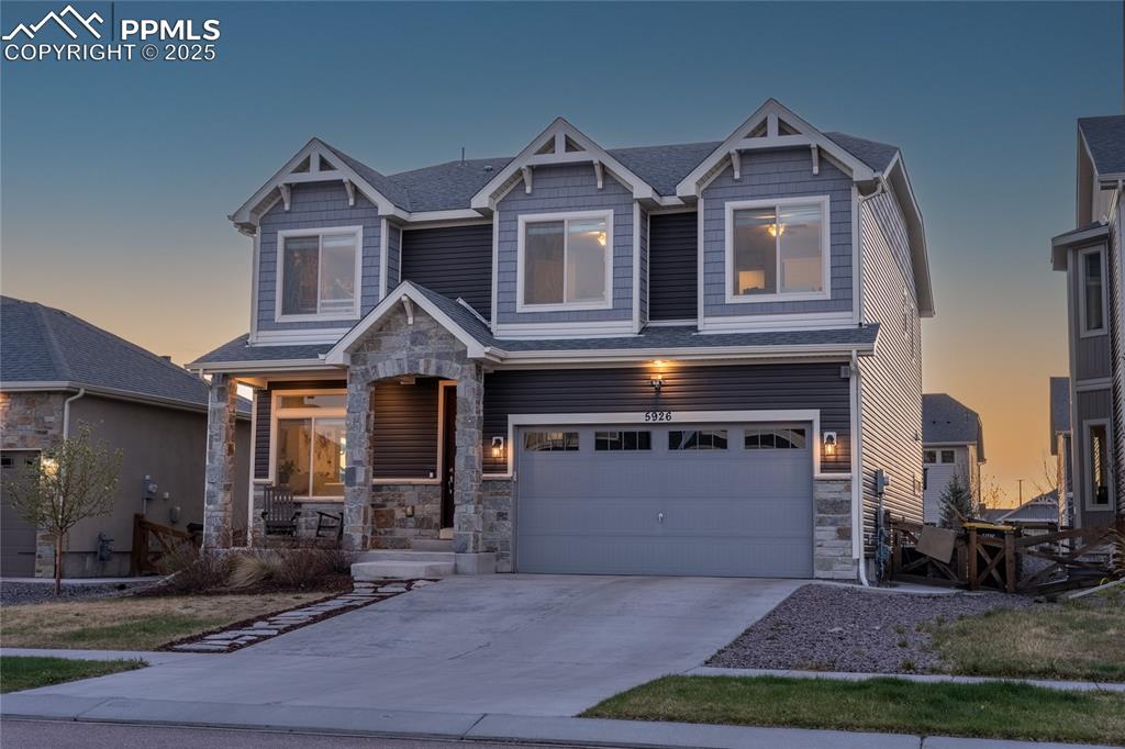 Image 3 of 48: Craftsman-style home featuring an attached garage, stone siding, covered po