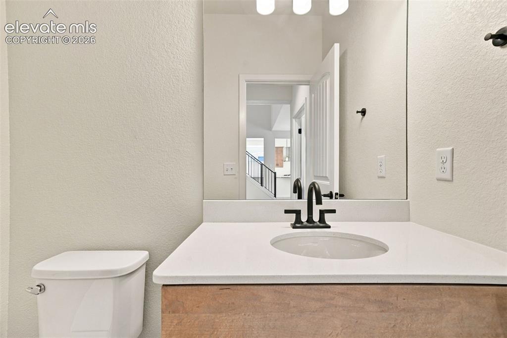 Image 23 of 49: Vanity with an undermount sink, quartz countertop, and maple cabinets with