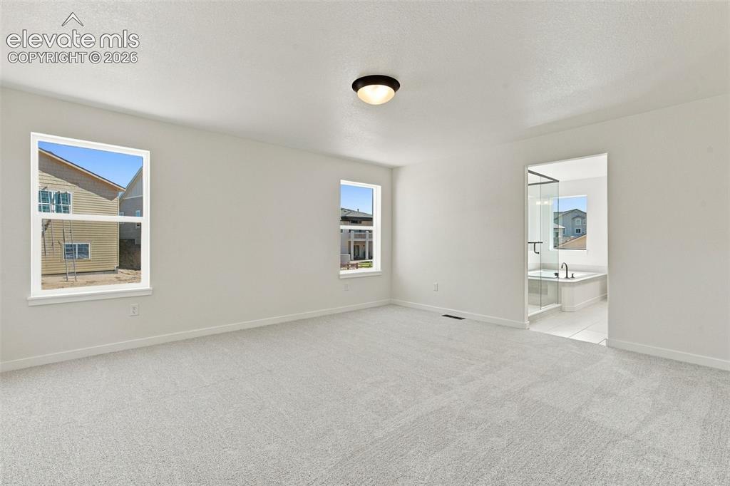 Image 24 of 49: Spacious Primary Bedroom room with soft white walls, light-light gray carpe