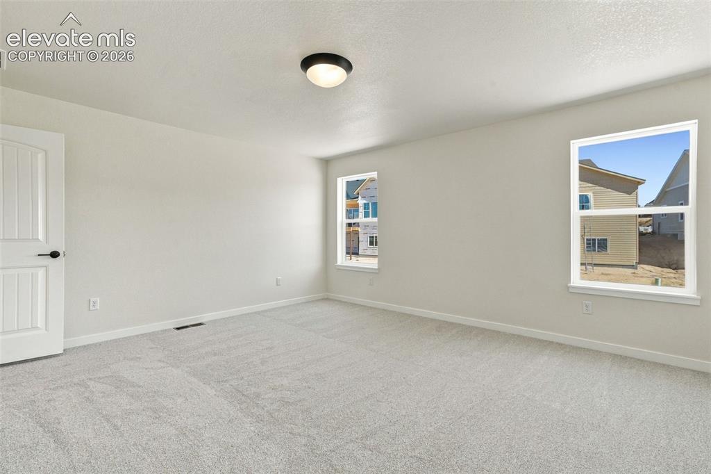 Image 25 of 49: Spacious Primary Bedroom room with soft white walls, light-light gray carpe