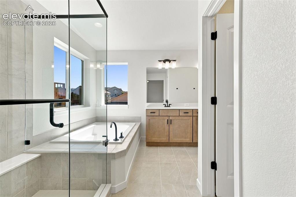 Image 27 of 49: Glass-enclosed shower with matte black hardware, built-in soaking tub with