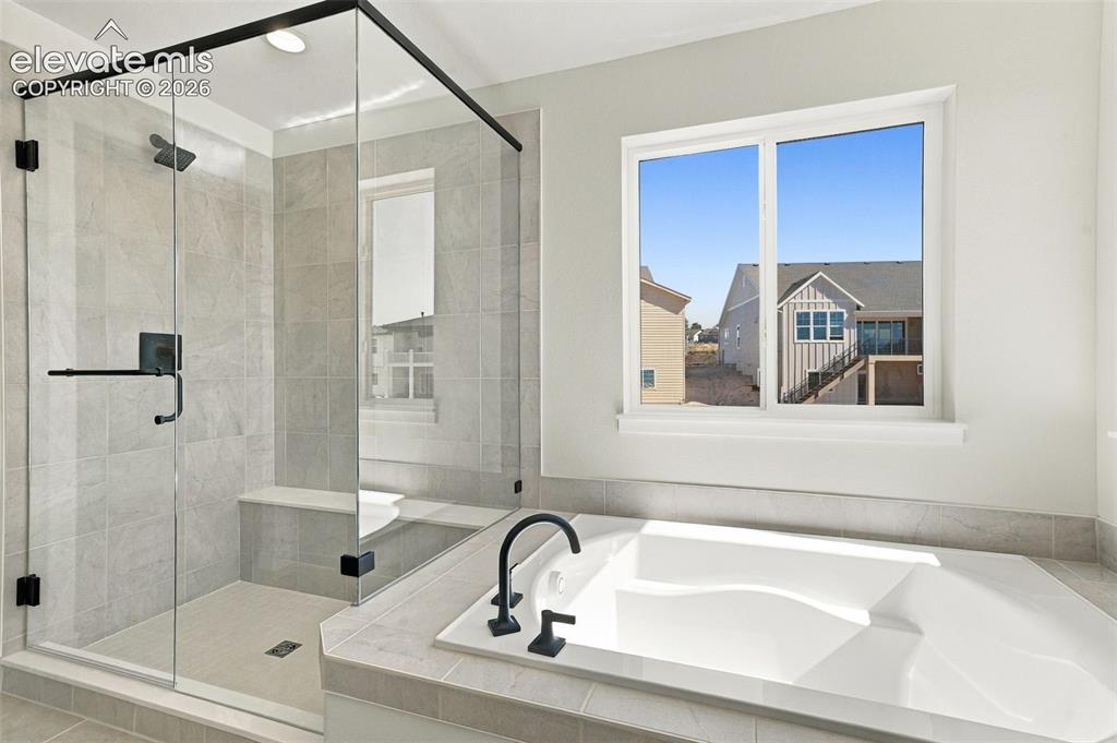 Image 29 of 49: Spacious bathroom featuring a built-in soaking tub with matte black fixture