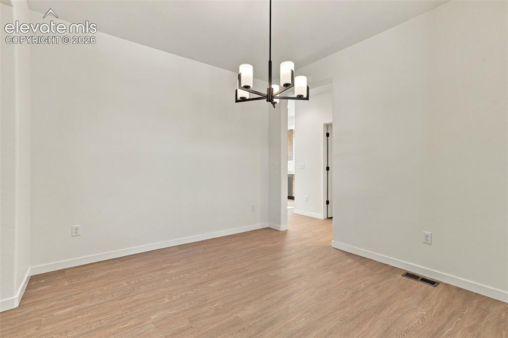 Image 5 of 49: Neutral-toned interior space featuring wood-finish flooring and a multi-arm