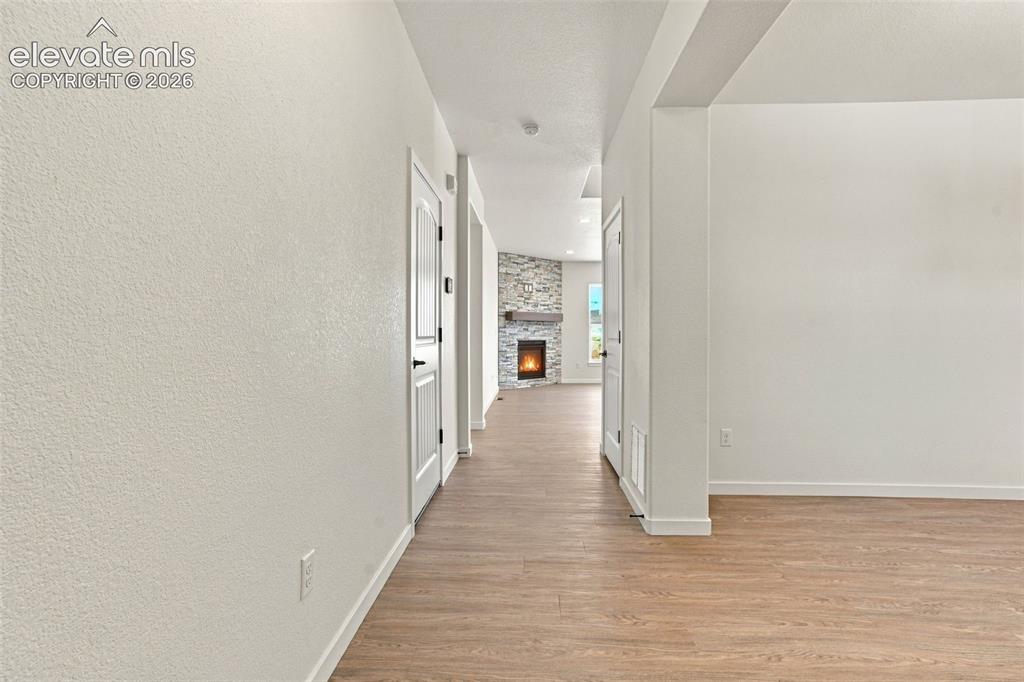 Image 7 of 49: Wood-finish flooring throughout, white interior doors, and a stone-clad fir