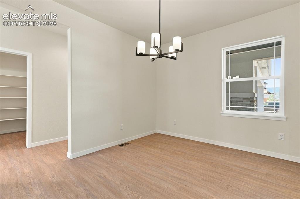 Image 8 of 49: Recessed shelving, wood-finish flooring, and a modern chandelier