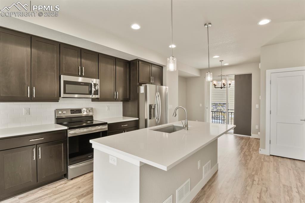 Image 9 of 29: Kitchen featuring stainless appliances, granite countertops and an island w