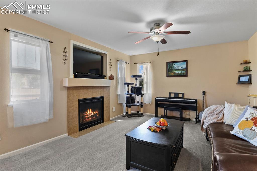 Image 6 of 49: Carpeted living room featuring ceiling fan and a tile fireplace