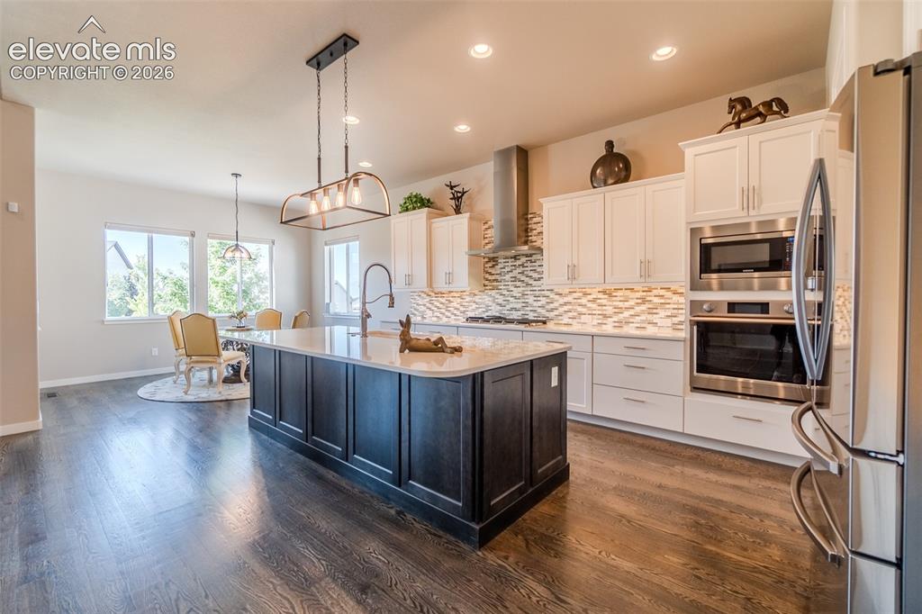 Image 12 of 50: Gourmet kitchen featuring a large central island with light-toned counterto