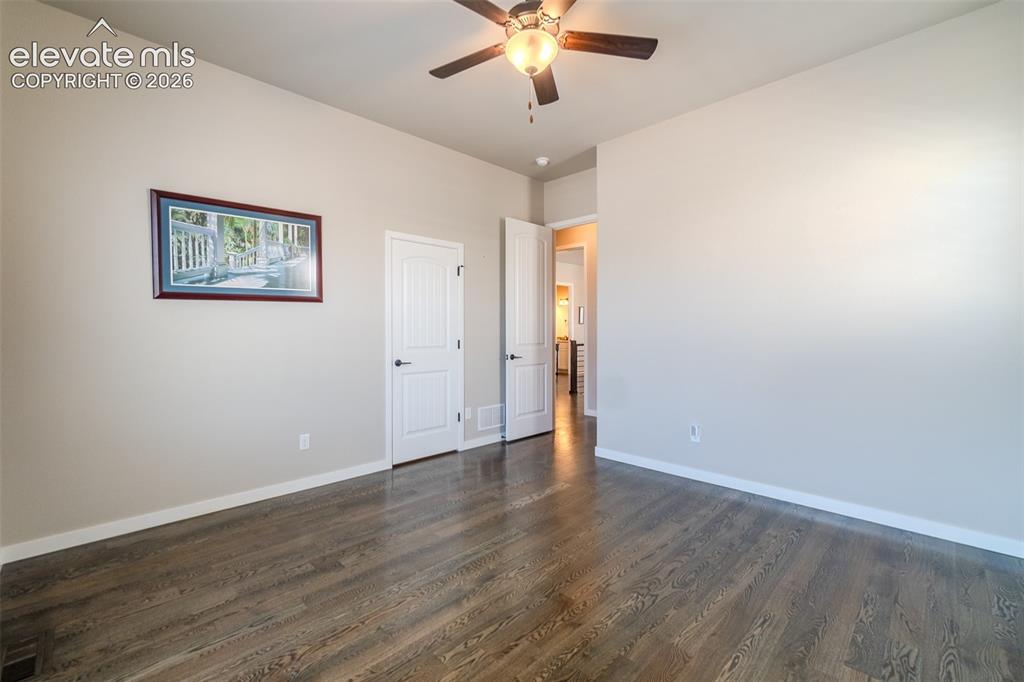 Image 16 of 50: Spacious room featuring wood-finish flooring, two windows with white louver