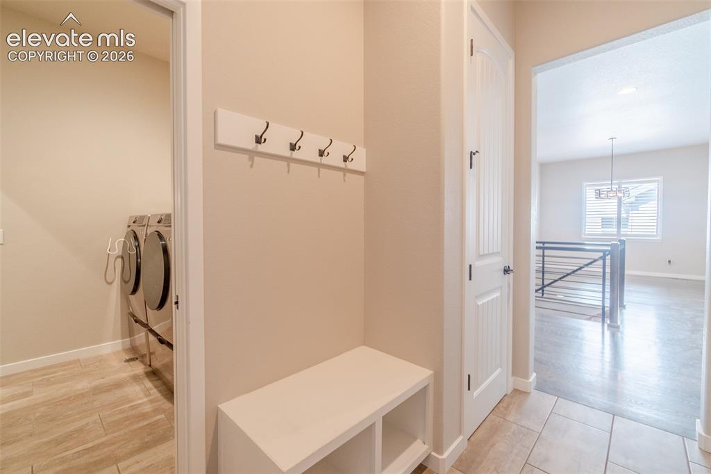 Image 18 of 50: Entryway featuring tiled flooring, built-in bench with storage, and coat ho