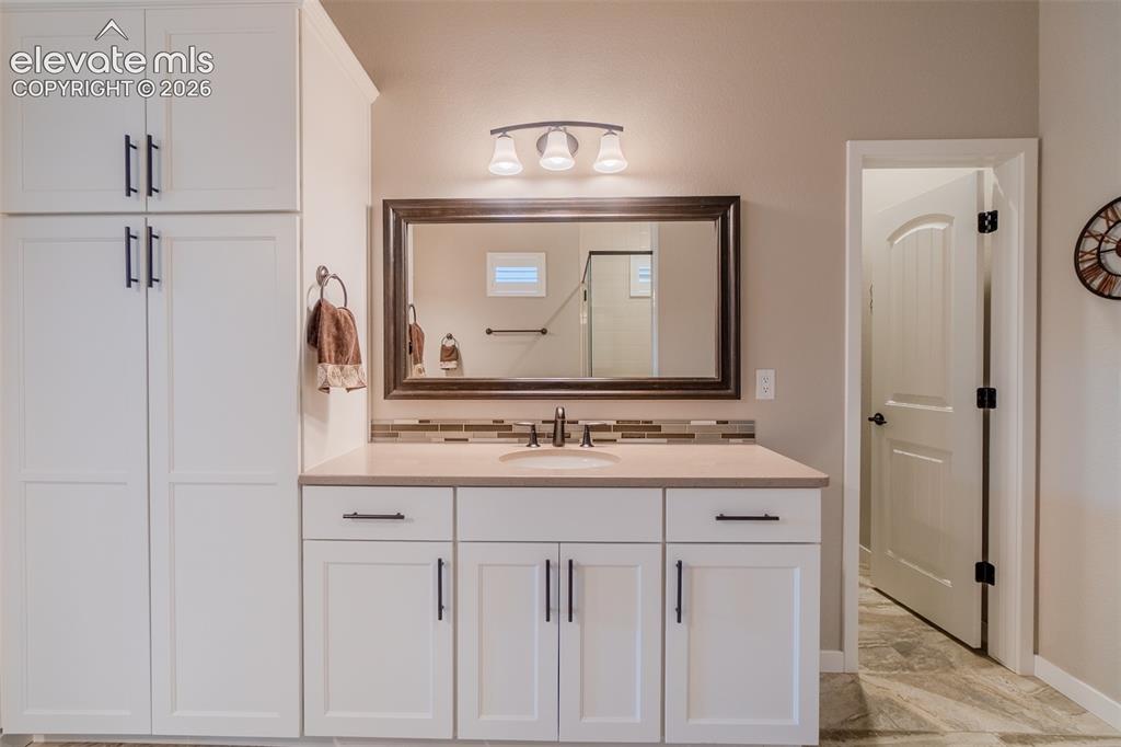 Image 23 of 50: Bathroom featuring a single vanity with light-colored countertop, integrate