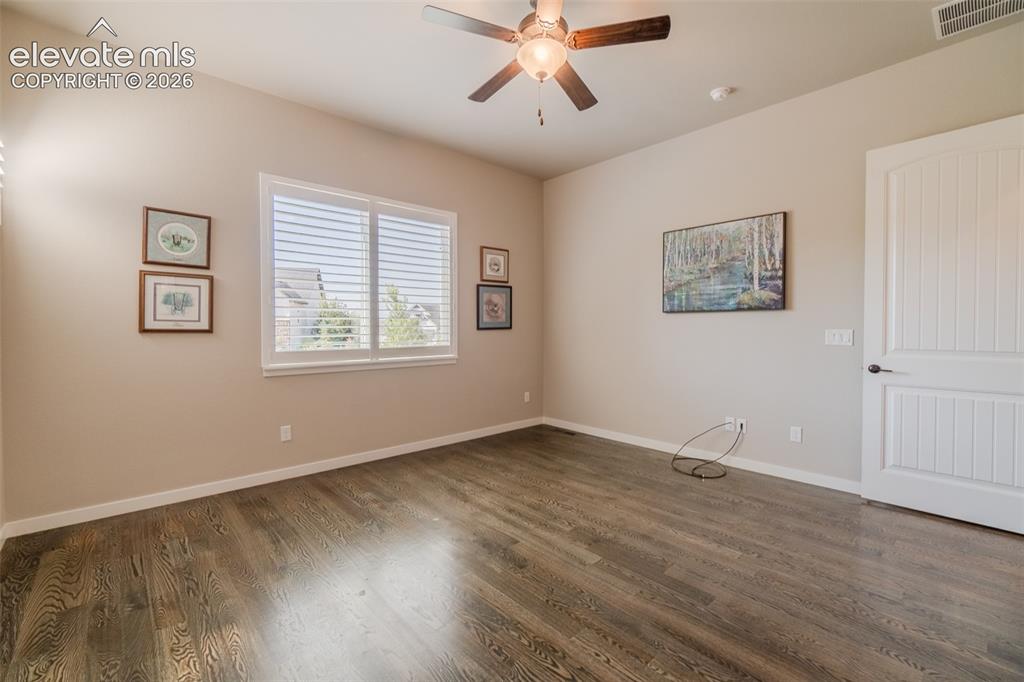 Image 25 of 50: Spacious room featuring wood-finish flooring, a ceiling fan with integrated
