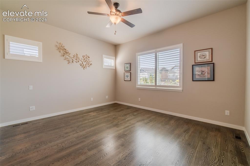 Image 28 of 50: Spacious room featuring wood-finish flooring, neutral-toned walls, and a ce