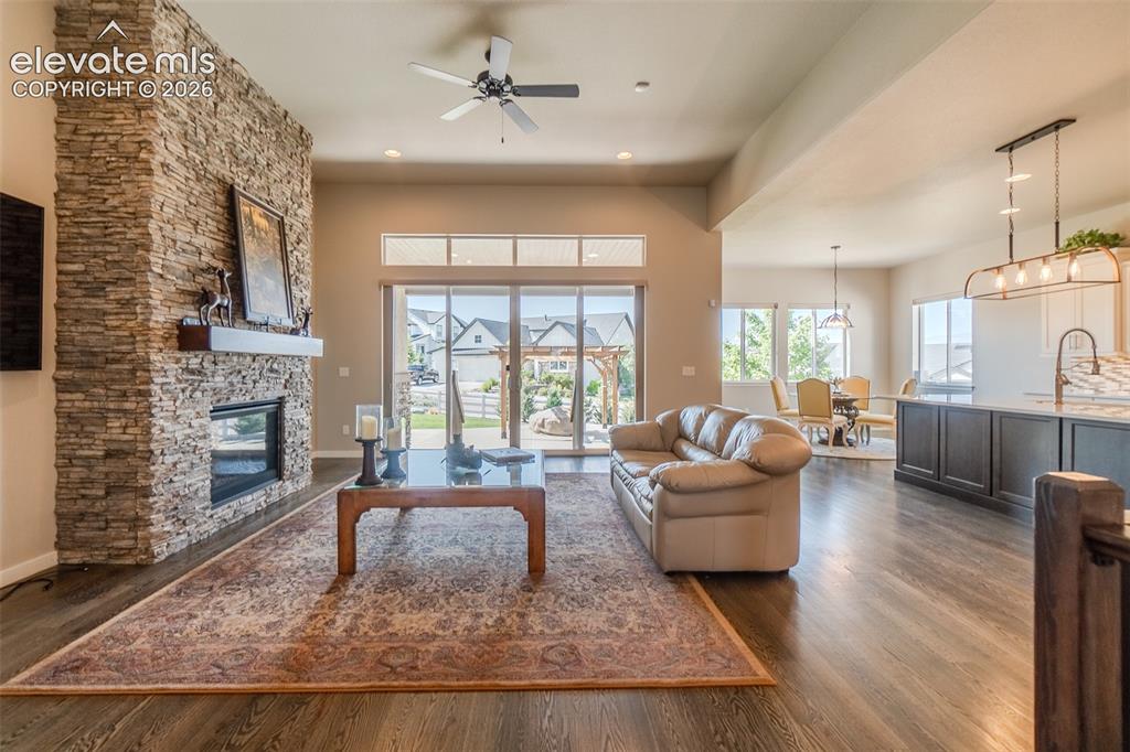 Image 3 of 50: Open-concept living space featuring a stacked stone fireplace with a wood m