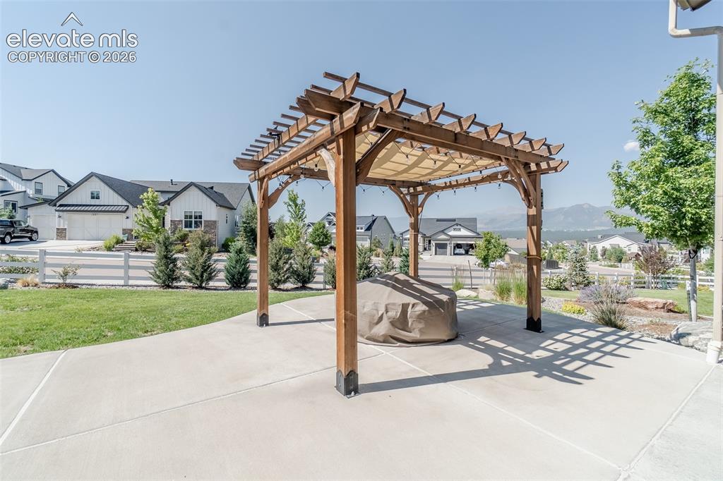 Image 30 of 50: Expansive concrete patio featuring a wood pergola with a fabric canopy
