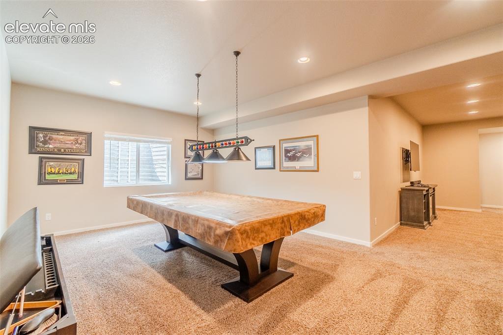 Image 34 of 50: Spacious recreation room featuring recessed lighting, a window with blinds,