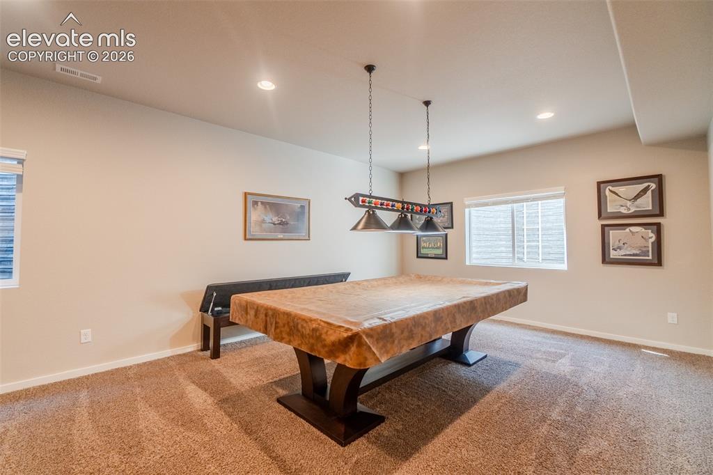Image 36 of 50: Recessed lighting illuminates the carpeted room, featuring a window with ho