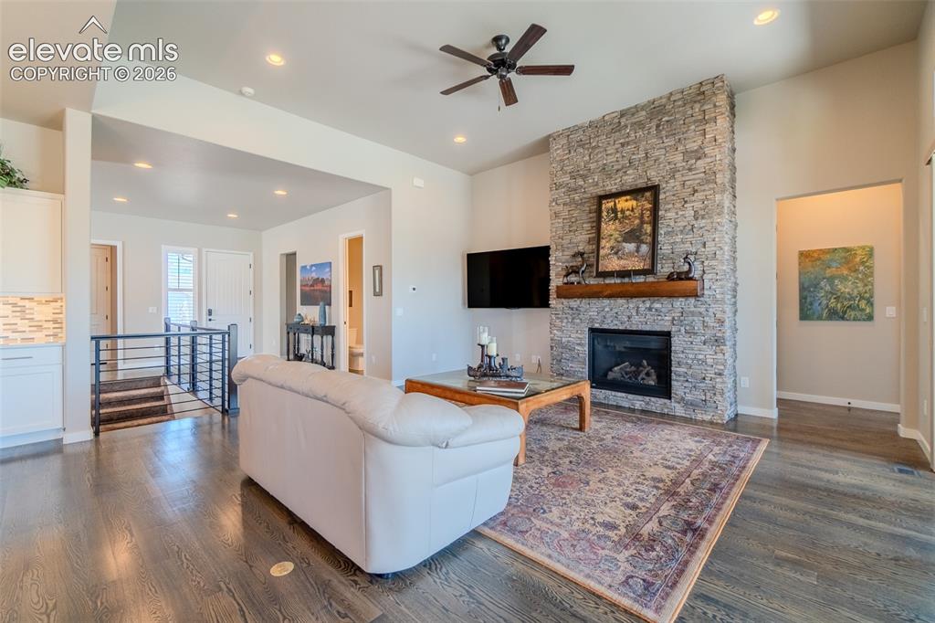Image 4 of 50: Living area featuring a stone-clad fireplace with a wood mantel, dark wood-