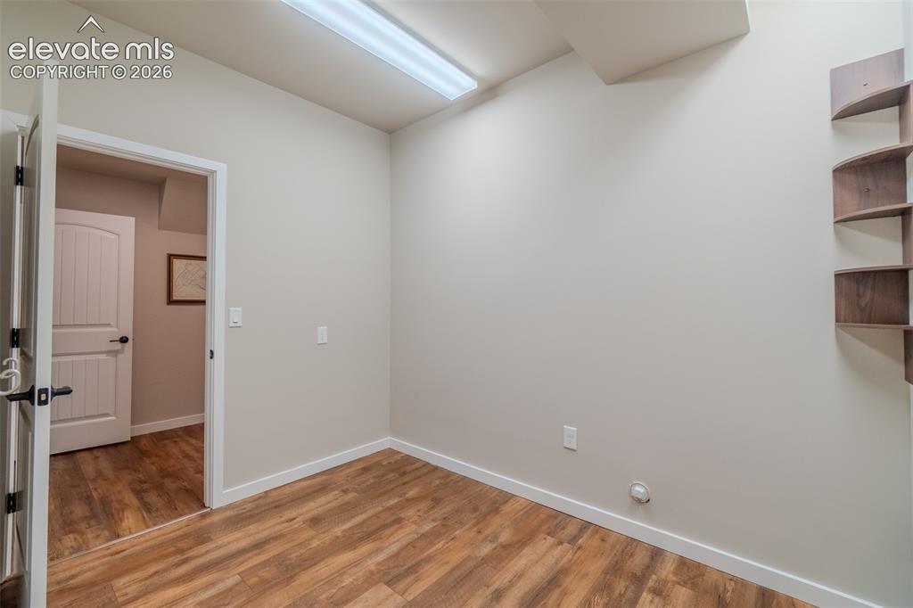 Image 41 of 50: Room featuring wood-finish flooring, light-toned walls, white trim, and a b