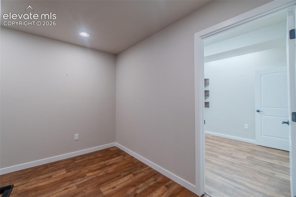 Image 43 of 50: Interior room featuring wood-finish flooring, recessed lighting, and a whit