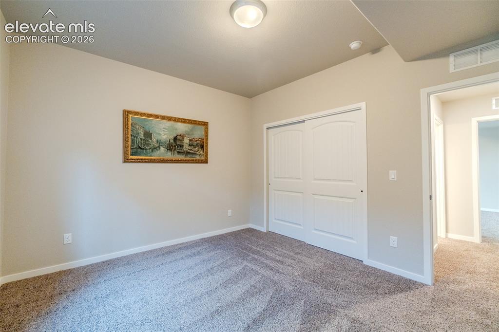 Image 45 of 50: Carpeted room featuring neutral wall tones, white baseboards, and a flush m
