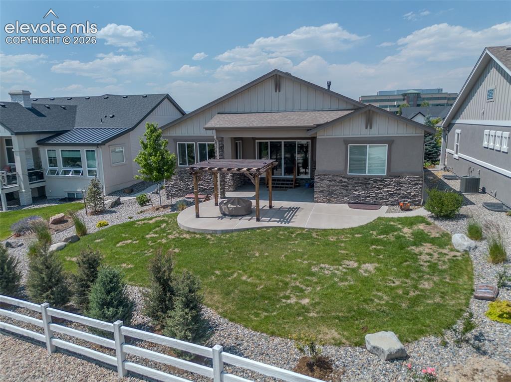 Image 46 of 50: Rear exterior featuring a concrete patio, wood pergola, and a built-in fire