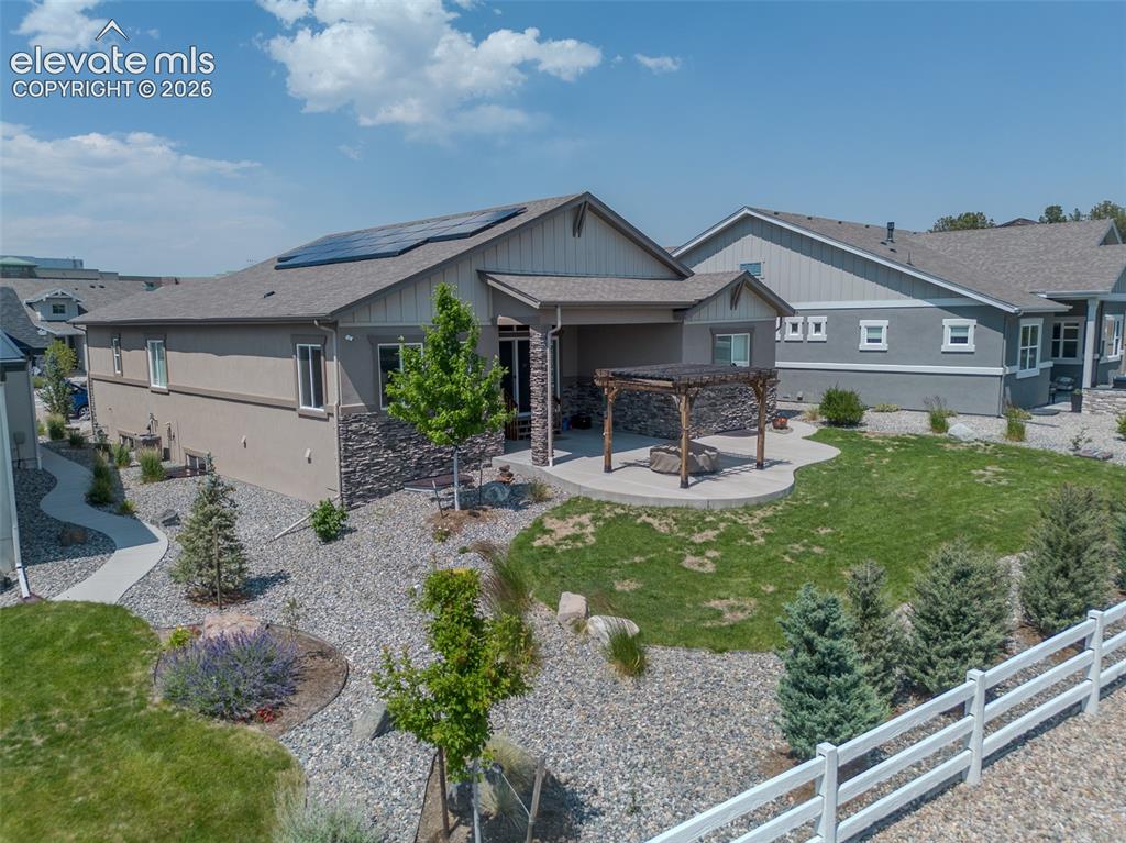 Image 47 of 50: Rear exterior featuring a covered patio, stone veneer accents, and a pergol