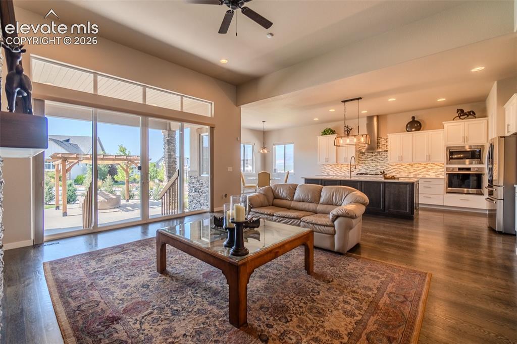 Image 5 of 50: Open-concept living area featuring wood-finish flooring and a stone-clad fi
