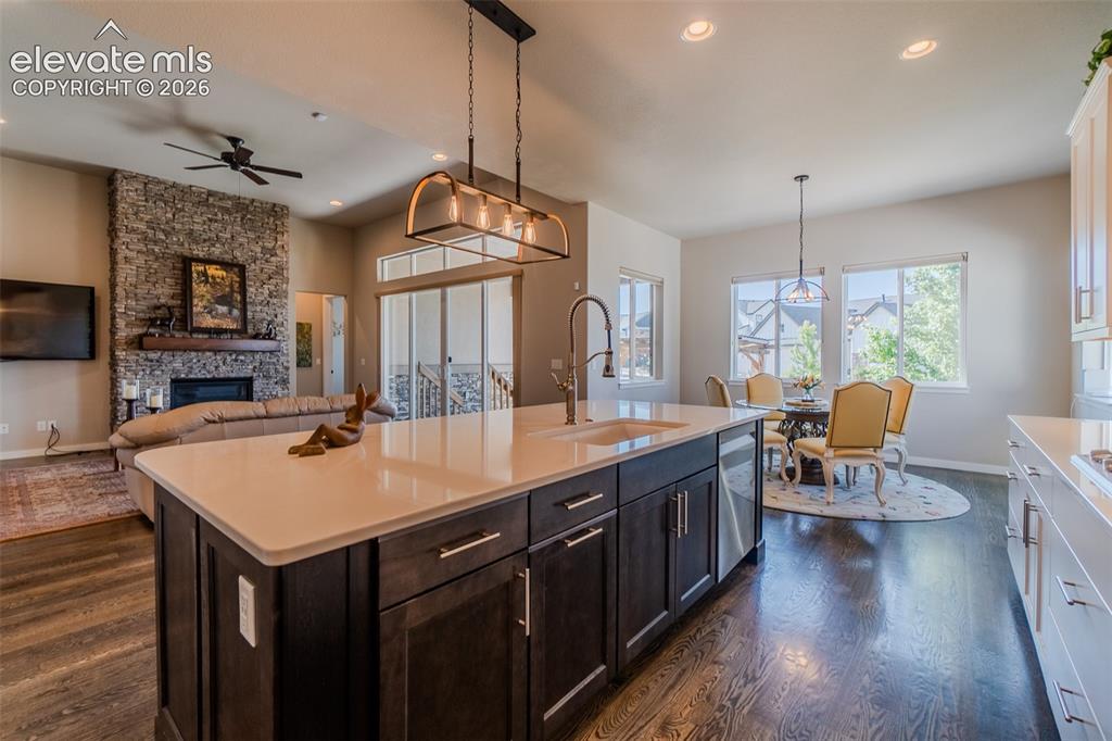 Image 7 of 50: Kitchen island featuring a white countertop, undermount sink, and dark wood