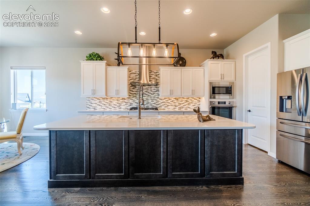 Image 9 of 50: Kitchen featuring an expansive center island with a light-toned countertop,