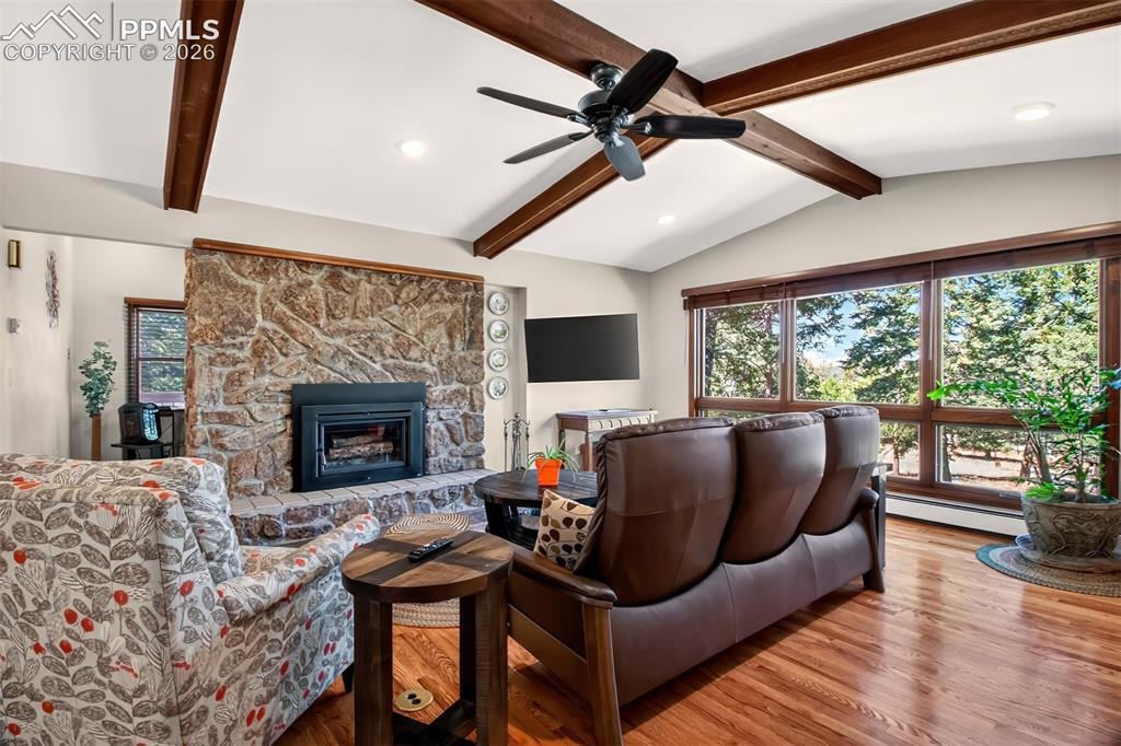 Image 6 of 50: Living room with hardwood flooring, vaulted wood beamed ceilings, a Lopi wo