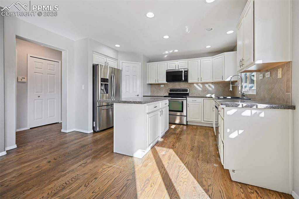 Image 12 of 49: Gorgeous kitchen with white cabinetry, granite countertops, stainless steel