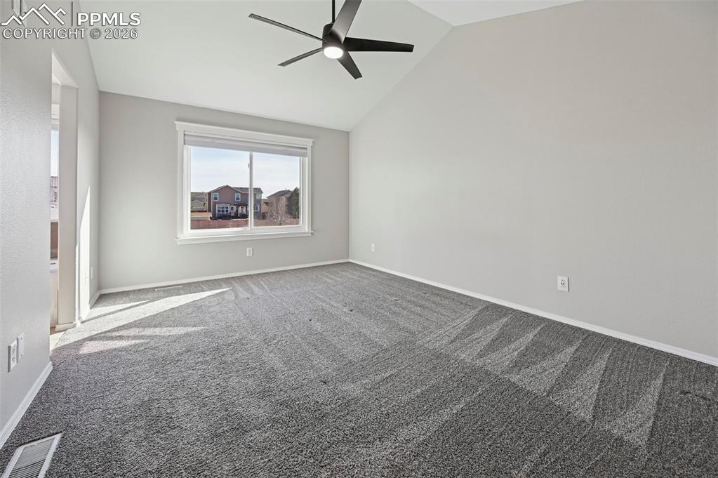 Image 17 of 49: Unstaged primary bedroom with vaulted ceilings, large designer walk-in clos