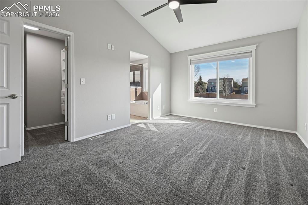 Image 18 of 49: Unstaged primary bedroom with vaulted ceilings, large designer walk-in clos