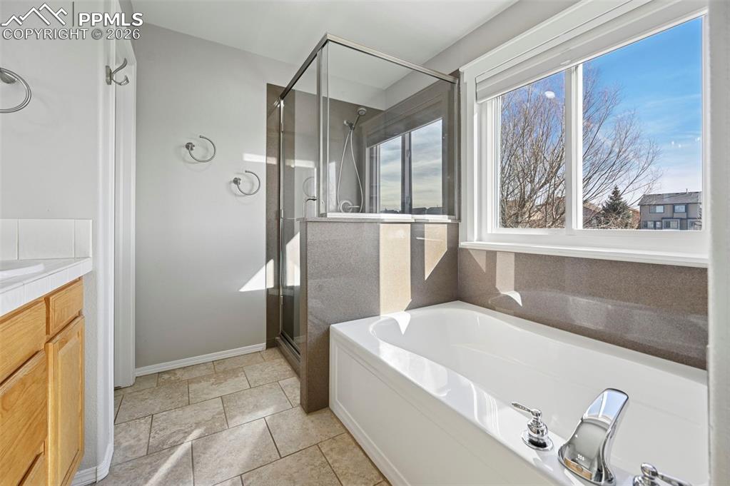 Image 21 of 49: Primary bathroom with double vanity, soaking tub, shower