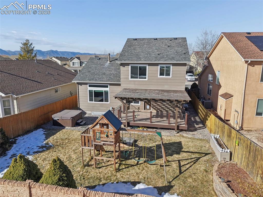 Image 44 of 49: Great backyard with pergola, hot tub, and play structure. Beautiful mountai