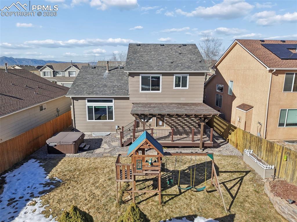 Image 45 of 49: Great backyard with Pergola, hot tub, and play structure. Beautiful mounta