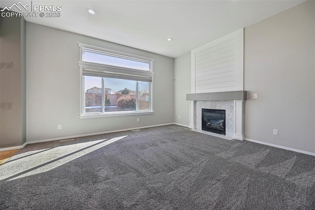 Image 6 of 49: Unstaged living room with beautiful fireplace, surrounded by hexagon tile,
