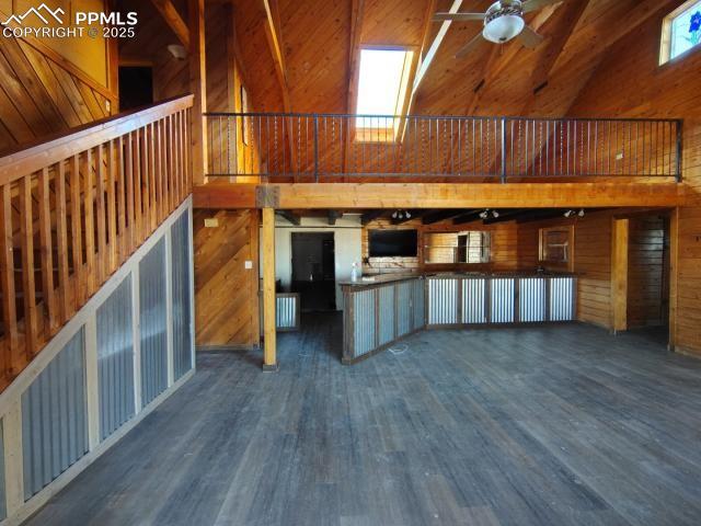 Image 2 of 2: Unfurnished living room featuring wood walls, dark wood-type flooring, high