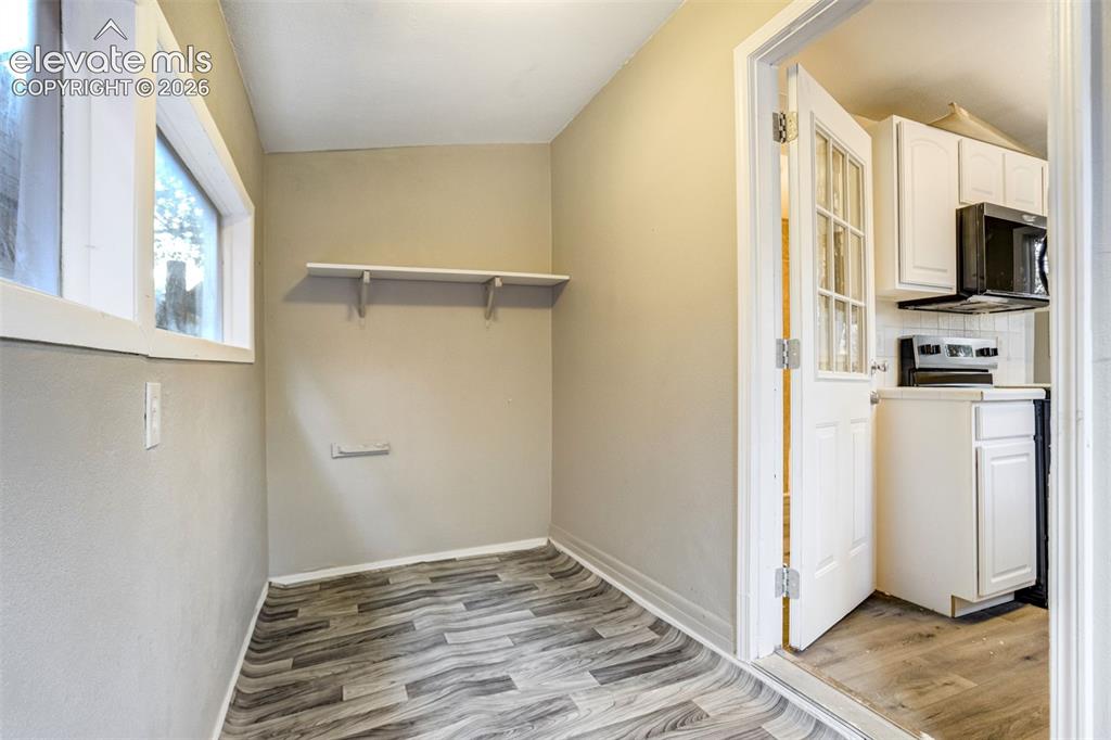 Image 19 of 28: Compact space featuring wood-finish flooring, two windows, and a built-in s