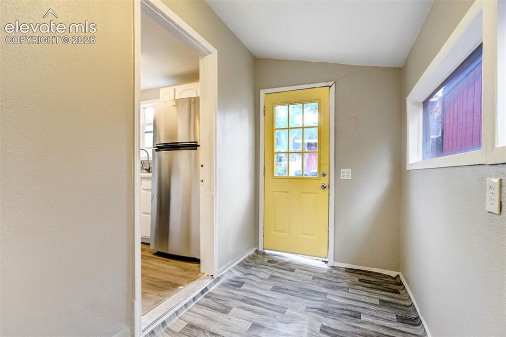Image 20 of 28: Entryway featuring wood-finish flooring, a vibrant yellow door with multipl