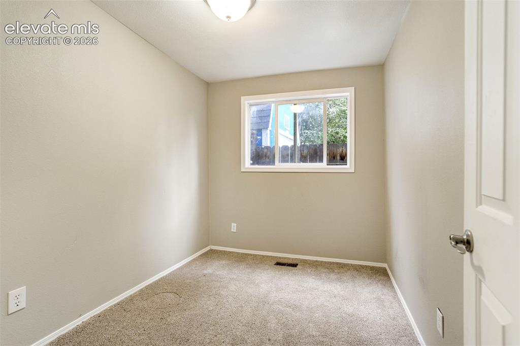 Image 23 of 28: Neutral-toned room featuring a single window and light-colored carpeting
