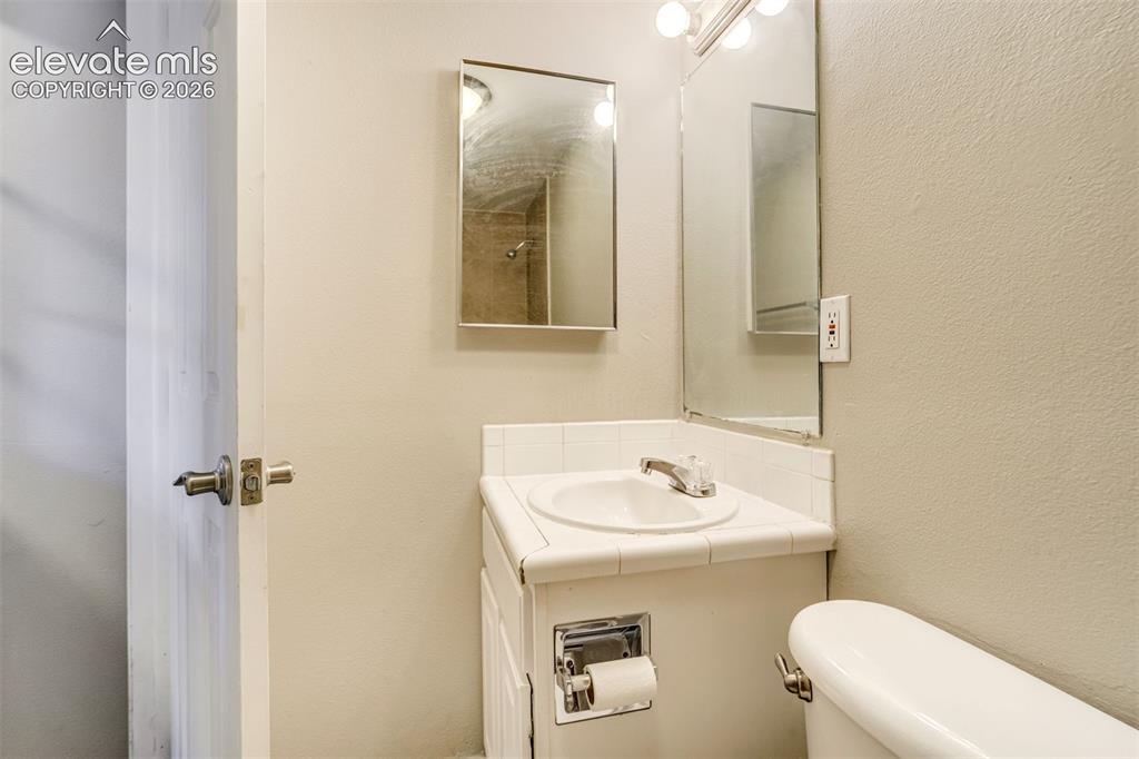 Image 26 of 28: Bathroom vanity with a round drop-in sink, chrome faucet, and white tiled c