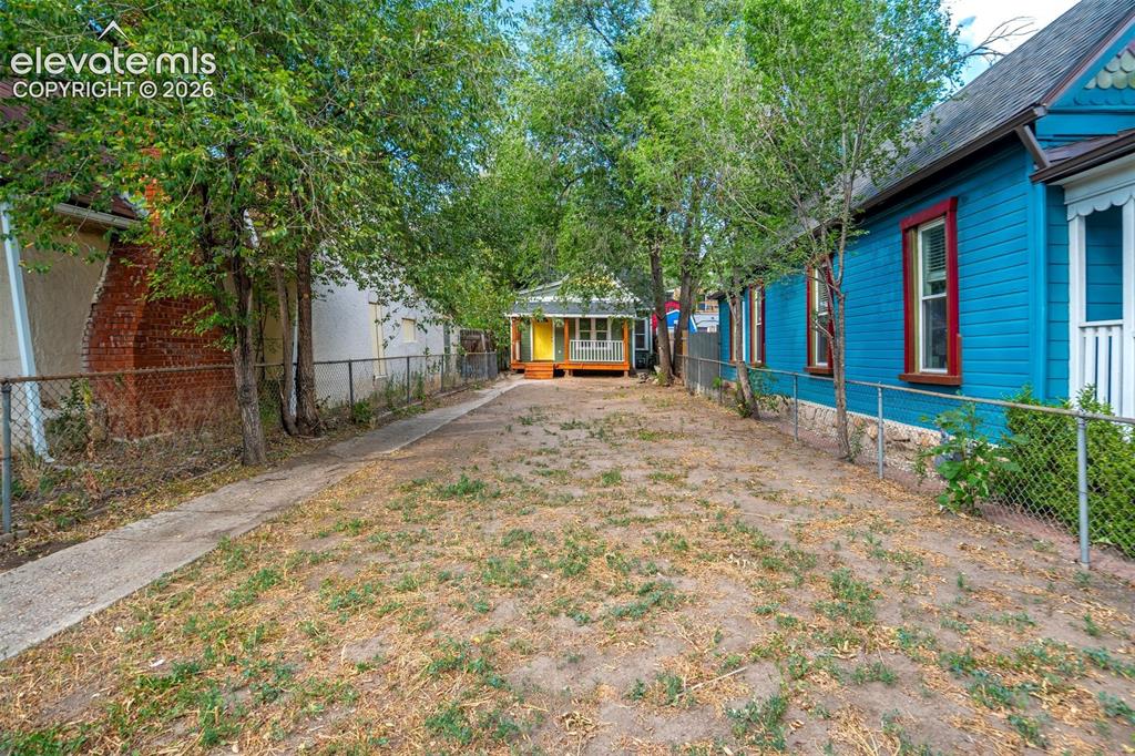 Image 3 of 28: Expansive outdoor space featuring a paved pathway, mature trees, and chain-