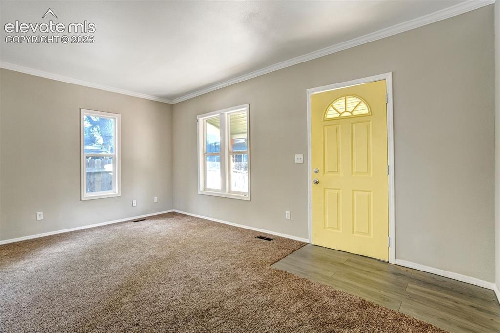 Image 7 of 28: Entry area with a bright yellow front door featuring an arched window detai