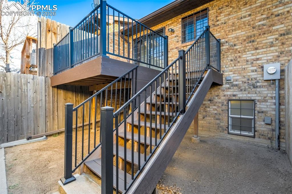 Image 32 of 37: The property features a brick exterior, a wooden deck with black metal rail