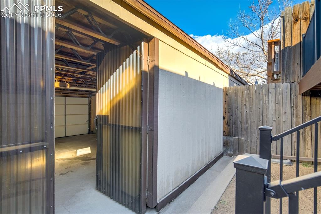 Image 34 of 37: The property features a garage with a roll-up door and a corrugated metal e