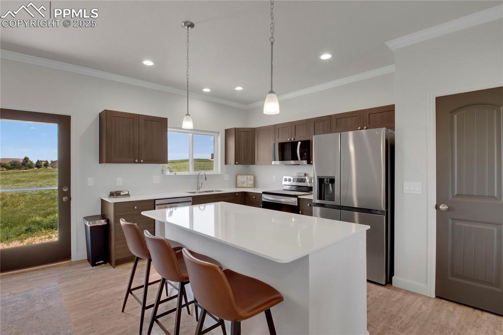 Image 10 of 25: Kitchen featuring stainless steel appliances, a kitchen bar, a kitchen isla